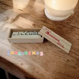 Dominó de madera en estuche rectangular con tapa deslizable, mostrando las fichas ordenadas sobre una mesa.